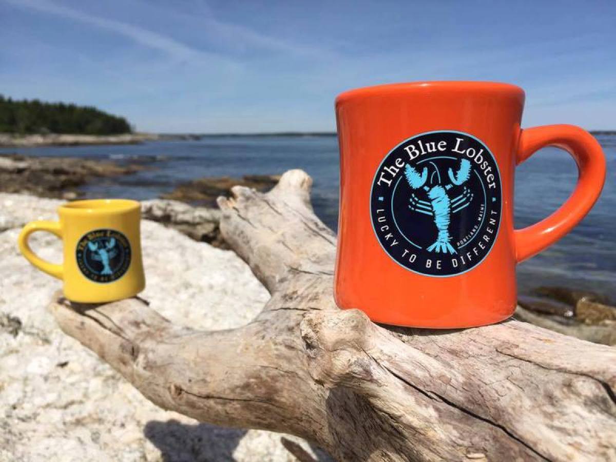 The Blue Lobster mugs against ocean background